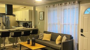 Ett modernt vardagsrum med en soffa, ett soffbord och en matplats med stolar.