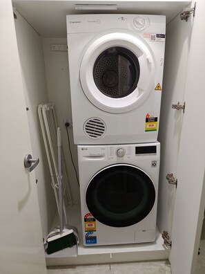 A stacked washer and dryer unit with energy and water rating labels, a QR code, and a safety warning label. - Bridge free waterfront Escape (Runaway Bay)