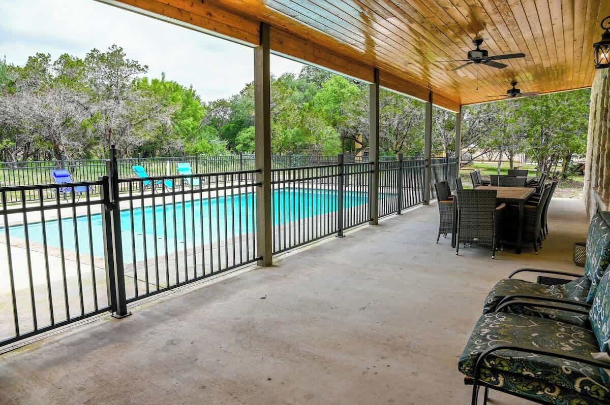 Un espace extérieur abrité comprenant une piscine, des sièges et une terrasse entourée d’une clôture.