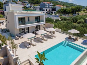 A modern hotel with a rooftop pool, outdoor seating, and a view of the surrounding neighborhood. - Exclusive new villa W H pool overlooking Split & Sea (Podstrana - Sv. Martin)