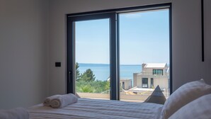 Un dormitorio con un amplio ventanal corredera que da a un balcón con vistas al mar.