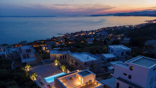 Una zona residencial costera con casas modernas, una piscina y vista al mar.