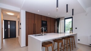 Una cocina moderna con una isla central, taburetes de madera y luces empotradas.