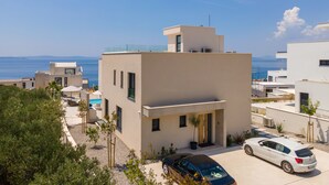 Un edificio moderno con techo plano, piscina y vista al mar.