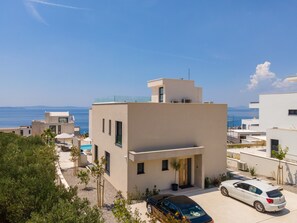 A modern building with a flat roof, a swimming pool, and a view of the sea. - Exclusive new villa W H pool overlooking Split & Sea (Podstrana - Sv. Martin)