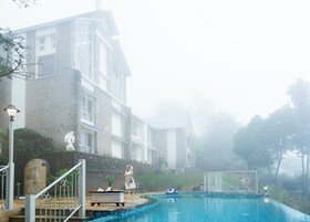 A pool area with a stone building, a statue, and a person standing by the pool.