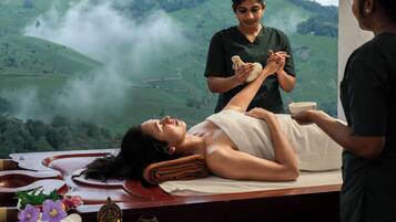 A massage therapy session with a scenic view of green hills and mist in the background.