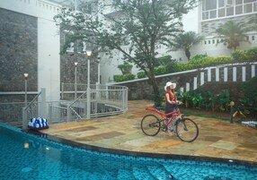 Zona de piscina con un muro de piedra, una bicicleta roja y una valla blanca.