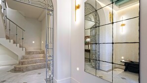 A staircase with a metal railing, a large mirror reflecting the room, and a wall-mounted light fixture. - Unique House With Private Terrace Casa Pilatos (Seville)
