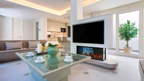 A modern living room with a glass coffee table, a sofa, a flat-screen TV, a fireplace, and a view of the kitchen. - Unique House With Private Terrace Casa Pilatos (Seville)