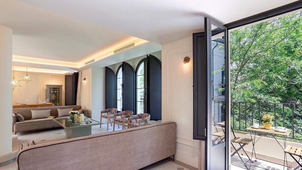 A modern living room with a sofa, chairs, a glass coffee table, and a balcony with outdoor furniture. - Unique House With Private Terrace Casa Pilatos (Seville)
