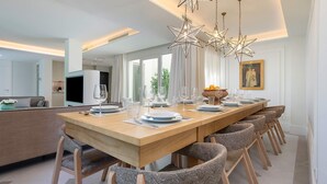 A modern dining area with a long wooden table, multiple chairs, and star-shaped pendant lights. - Unique House With Private Terrace Casa Pilatos (Seville)