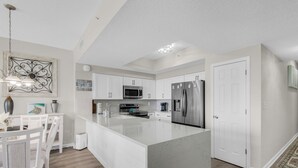 Una cocina moderna con armarios blancos, electrodomésticos de acero inoxidable y una isla de mármol.