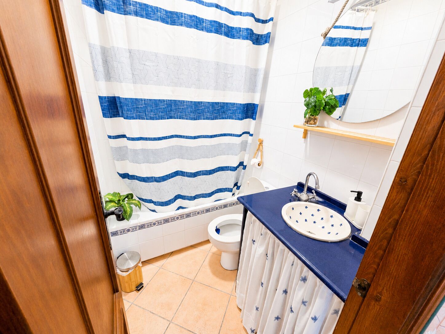 A bathroom with a striped shower curtain, a toilet, a sink with a blue countertop, and a mirror above the sink.