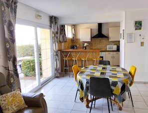 A dining area with a table covered in a checkered tablecloth, yellow chairs, and a sofa with a patterned cushion. - Cottage 'Gite Aquillon' with Sea View, Private Terrace and Wi-Fi (Audinghen)