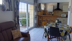 Un espace repas comprenant une table, des chaises, un canapé et une cuisine en arrière-plan.