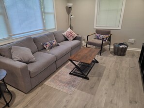A living room with a grey sofa, a wooden coffee table, a patterned rug, a floor lamp, and a wicker basket. - Wanda Way Gorgeous 3-bedroom house with AC in charming Pensacola (Pensacola)