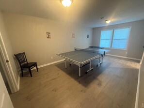 A room with a ping pong table, a chair, and a window with blinds. - Wanda Way Gorgeous 3-bedroom house with AC in charming Pensacola (Pensacola)