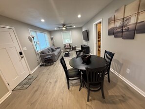A modern living room with a sofa, coffee table, and dining area with chairs. - Wanda Way Gorgeous 3-bedroom house with AC in charming Pensacola (Pensacola)