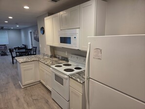 A modern kitchen with white cabinetry, a built-in microwave, a stove, and a refrigerator. - Wanda Way Gorgeous 3-bedroom house with AC in charming Pensacola (Pensacola)