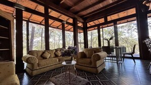 A spacious room with a wooden ceiling, large windows, a sofa, a coffee table, and a rug. - Constanza de GEstores (Huasca De Ocampo)