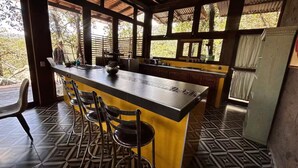 A kitchen with a bar area, a refrigerator, and a window with a view of trees. - Constanza de GEstores (Huasca De Ocampo)