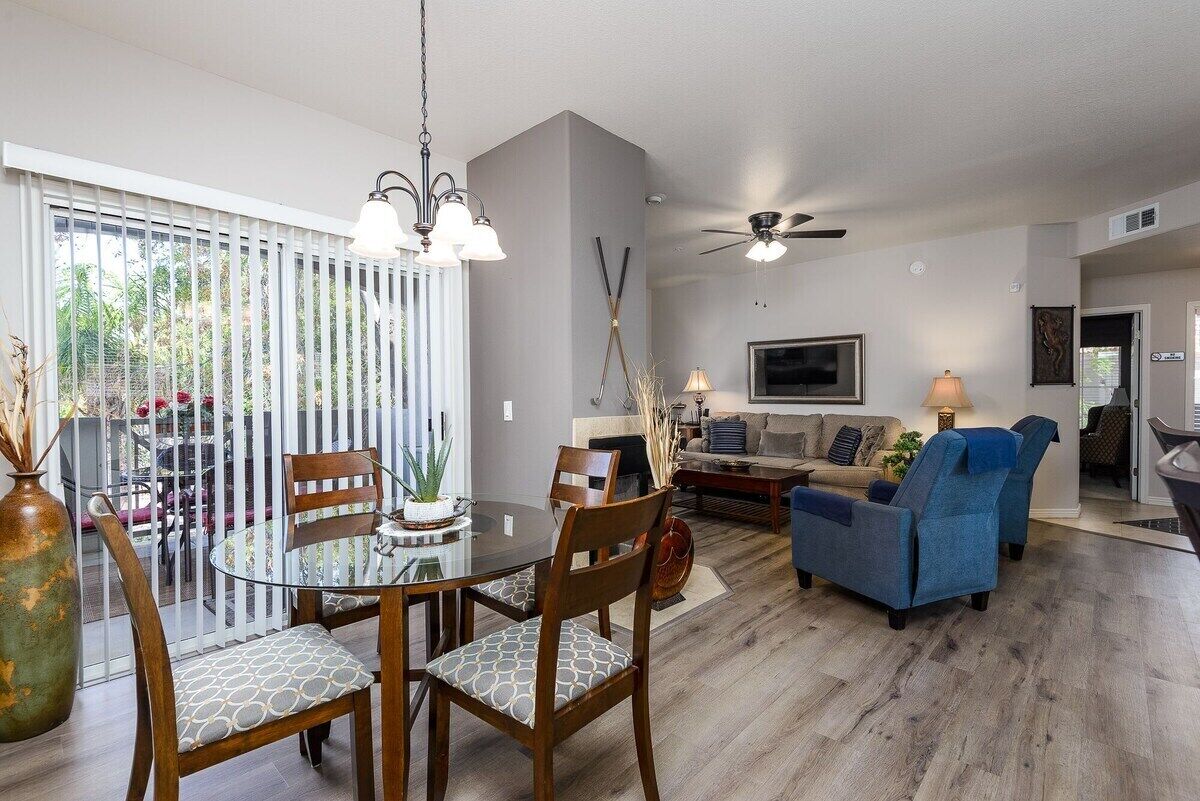 A modern living room with a dining table, chairs, a sofa, and a TV.