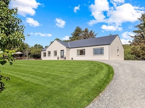 A modern two-story house with a well-maintained lawn and a gravel driveway. - Owen Glen Cottage Modern Holiday Home Near Clifden Town (Clifden)