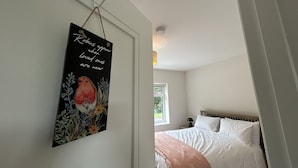 A bedroom with a bed, a bedside table, and a wall-mounted artwork. - Owen Glen Cottage Clifden (Clifden)