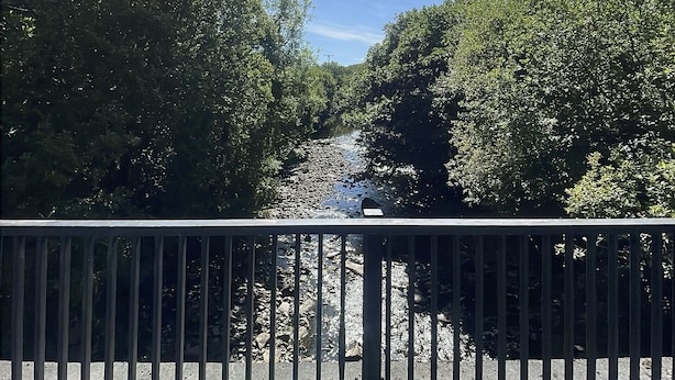 A wooden bridge with metal railings, a clear sky, and a river below. - Owen Glen Cottage Clifden (Clifden)