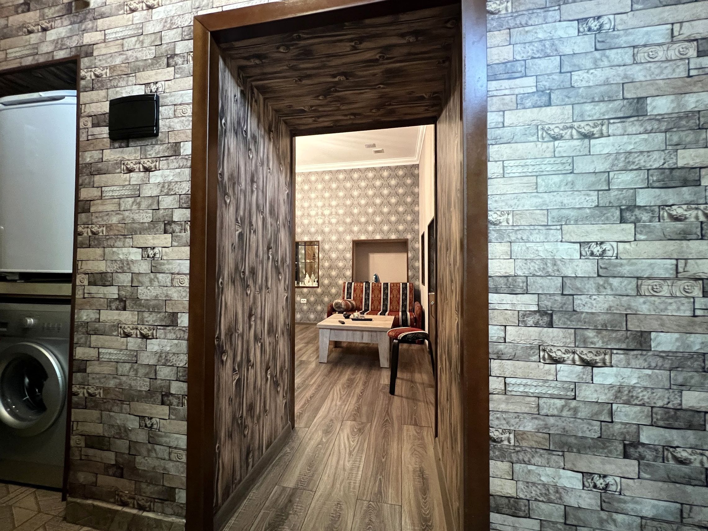 A narrow hallway with a stone wall on one side and a wooden door frame on the other.