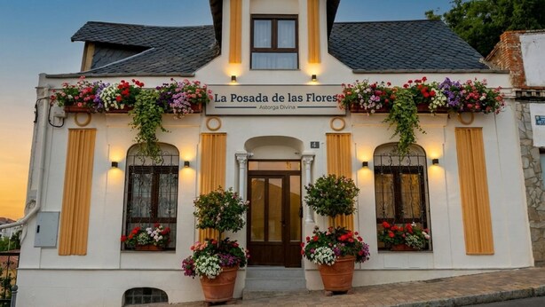 A building with a sign reading 'La Posada de las Flores' and 'Astorga Divina.' It features a symmetrical facade with a central entrance, flanked by windows with flower boxes. - Las Posada de las Flores (Astorga)