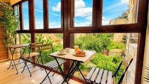 A balcony with a table set for breakfast, chairs, and a potted plant. - Las Posada de las Flores (Astorga)