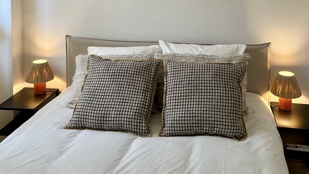Et hotelværelse med en seng, to sengeborde med lamper og tre billeder på væggen.