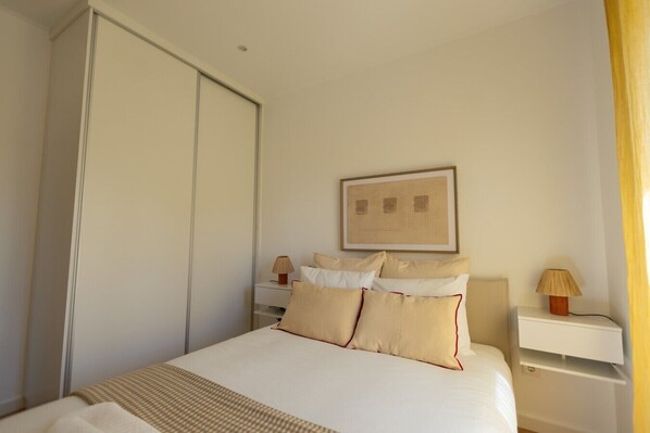 A hotel room with a bed, bedside tables, a wardrobe, and a framed picture on the wall. - Modern Haven in Amadora (Amadora)
