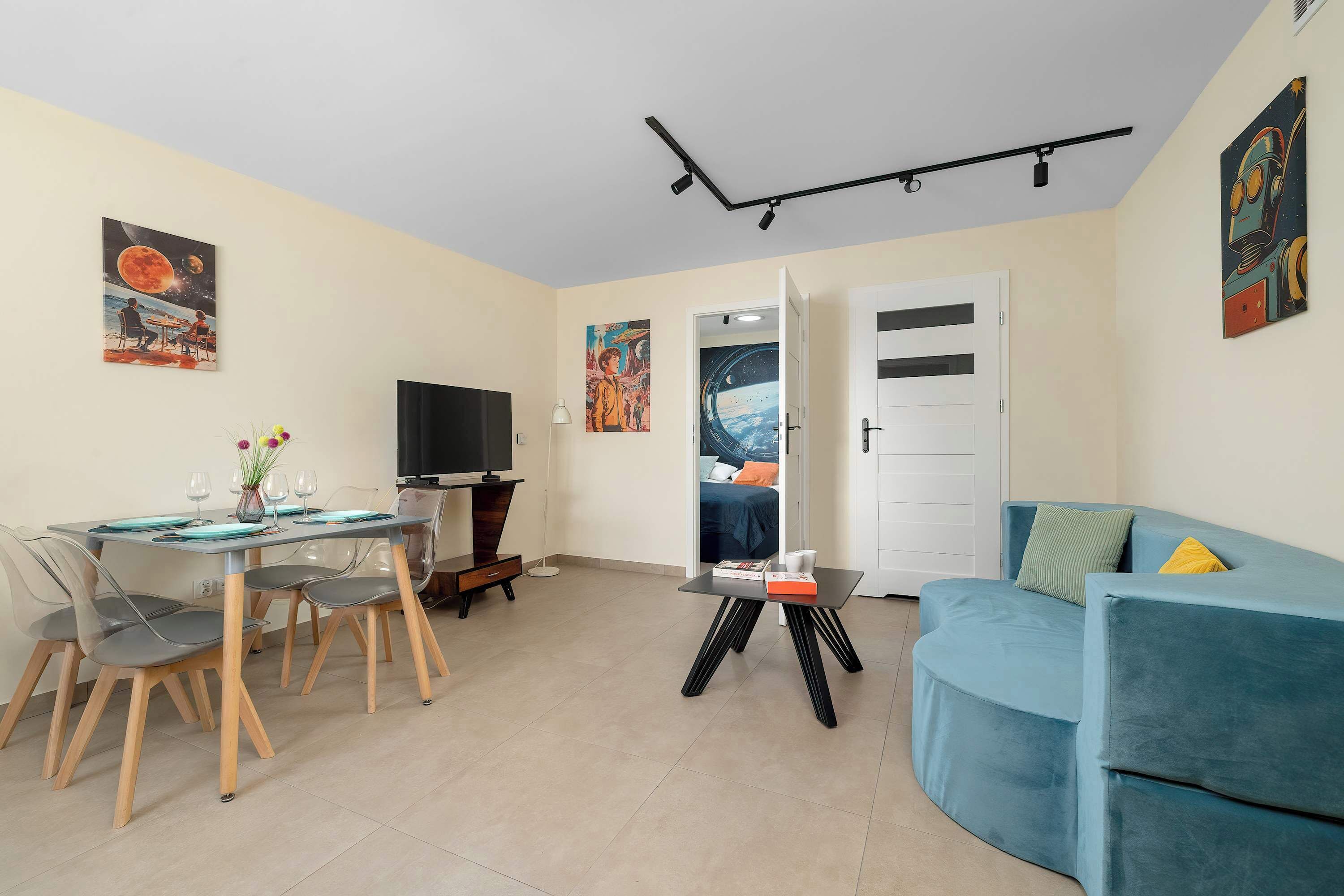 A modern living room with a dining area, a flat-screen TV, and artwork on the walls.