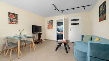 A modern living room with a dining area, a flat-screen TV, and artwork on the walls.