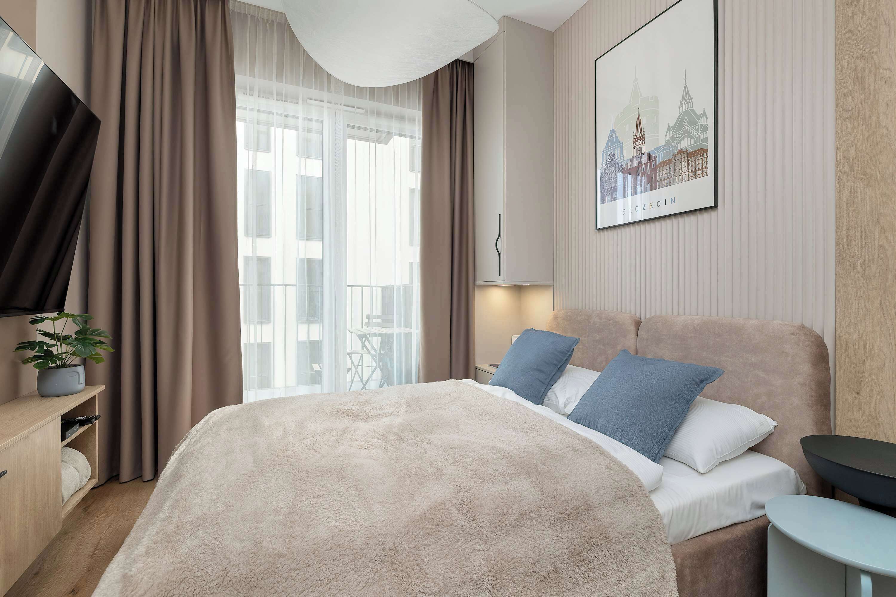 Une chambre d’hôtel moderne avec un grand lit, une télévision, une petite table et une plante en pot.