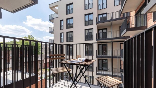A balcony with a table, chairs, and a view of a multi-story building. - Beige Studio with Balcony | By the River (Szczecin)