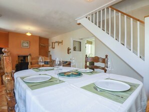 A dining area with a table set for four, a staircase, and a view of the living room. - Fairsands (Redruth)
