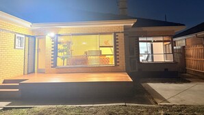 Una casa moderna con patio, garaje a la vista y jardín trasero cercado.