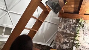 Une pièce avec un plafond en pente, un mur en pierre et une fenêtre.