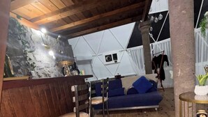 Un intérieur chaleureux avec un plafond en bois, un canapé bleu et un coin bar avec des tabourets.