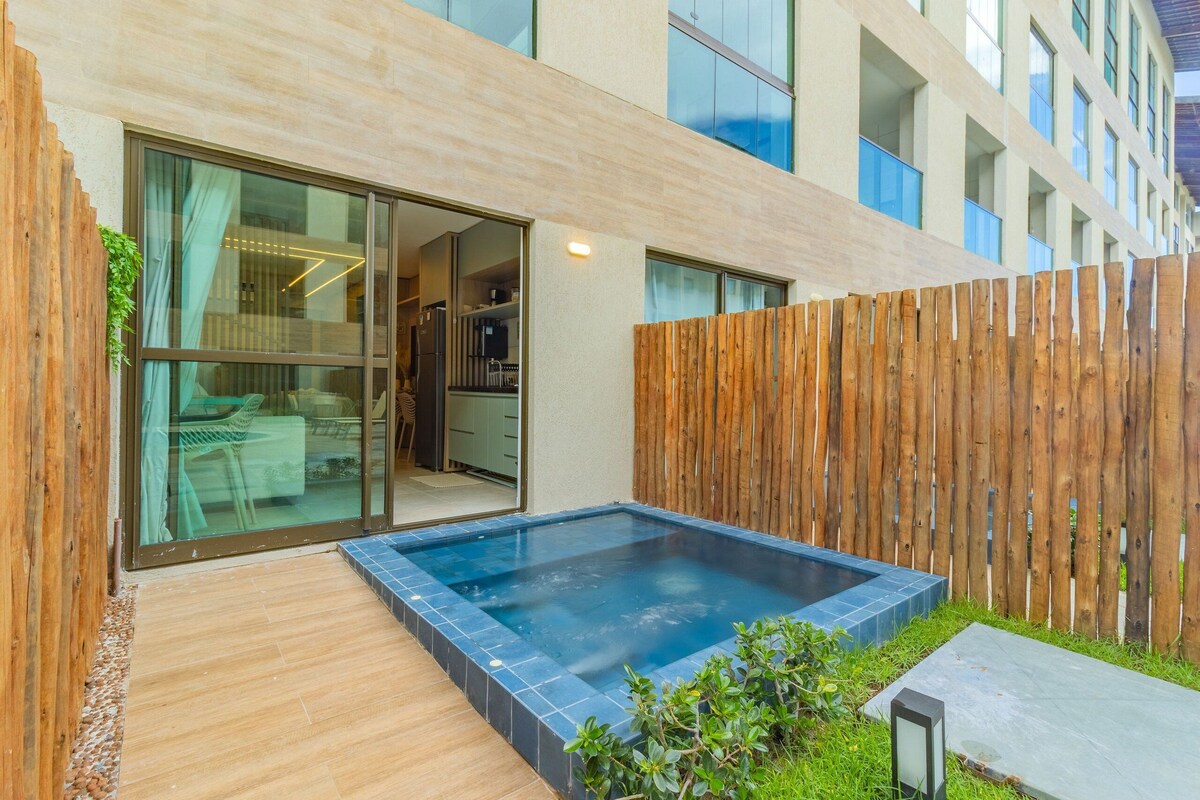Un edificio moderno con un cerramiento de madera, una puerta de cristal que da a una habitación y un pequeño espacio exterior con hidromasaje.