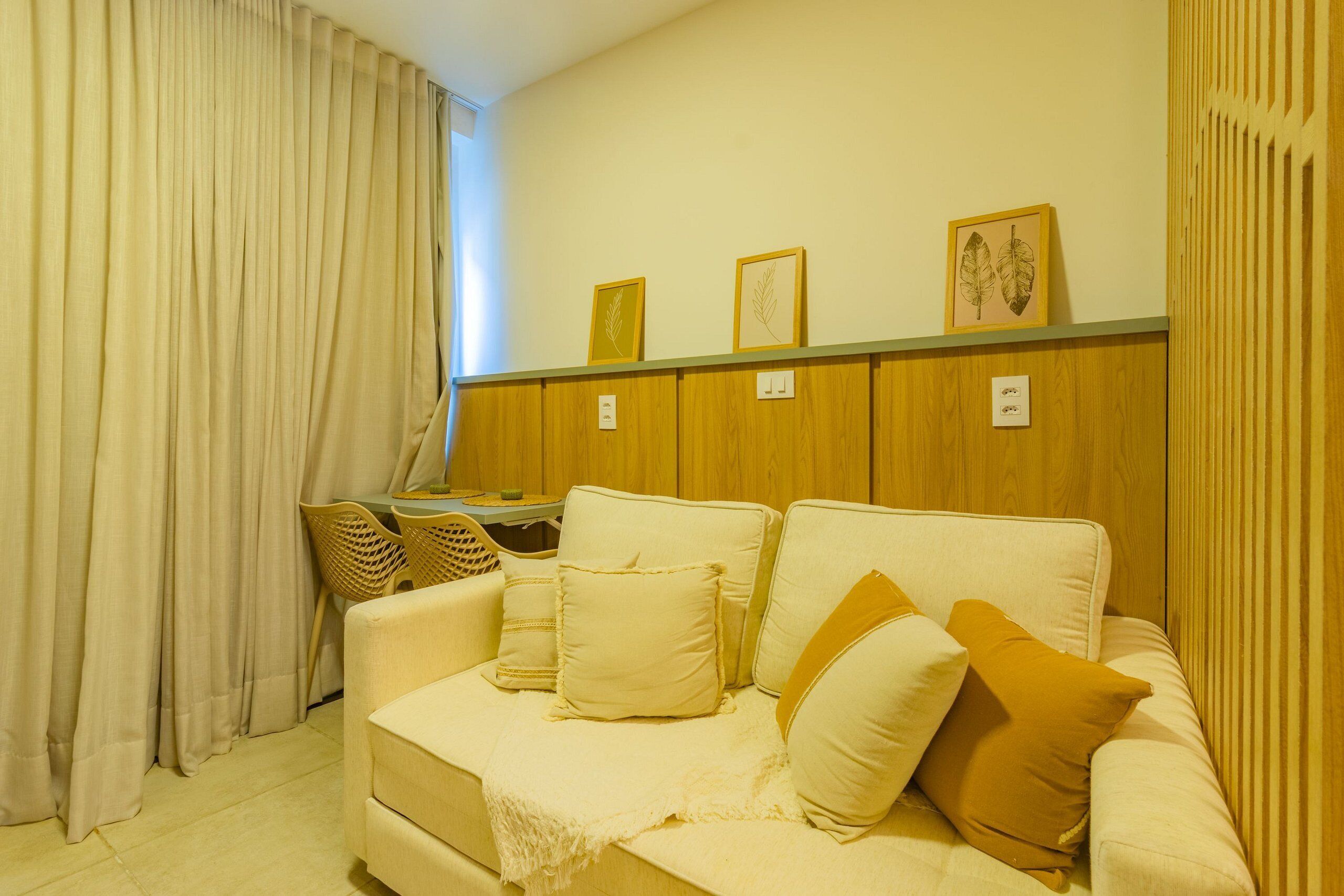 A room with a sofa, a table, and a chair. There are framed pictures on the wall.