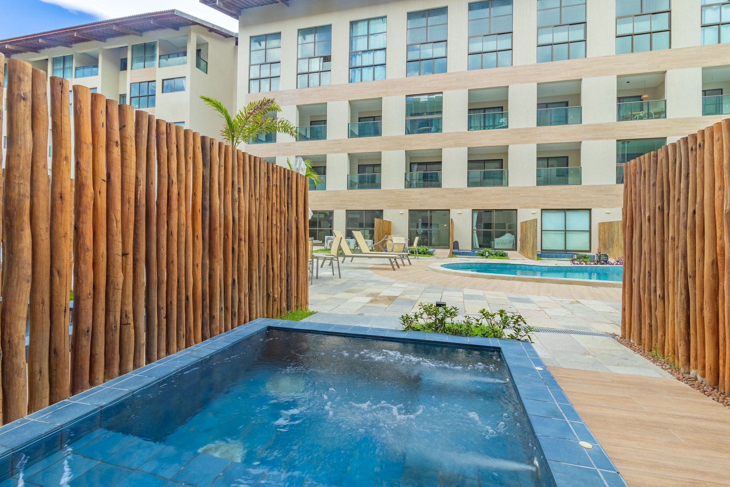 Um hotel moderno com piscina, cercas de madeira e área de spa.