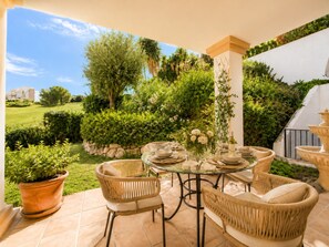 An outdoor patio with wicker furniture, a glass table, and a decorative fountain. - Frontline Golf Villa in the stunning La Cala Golf. Perfect for families and golfers! (Mijas)