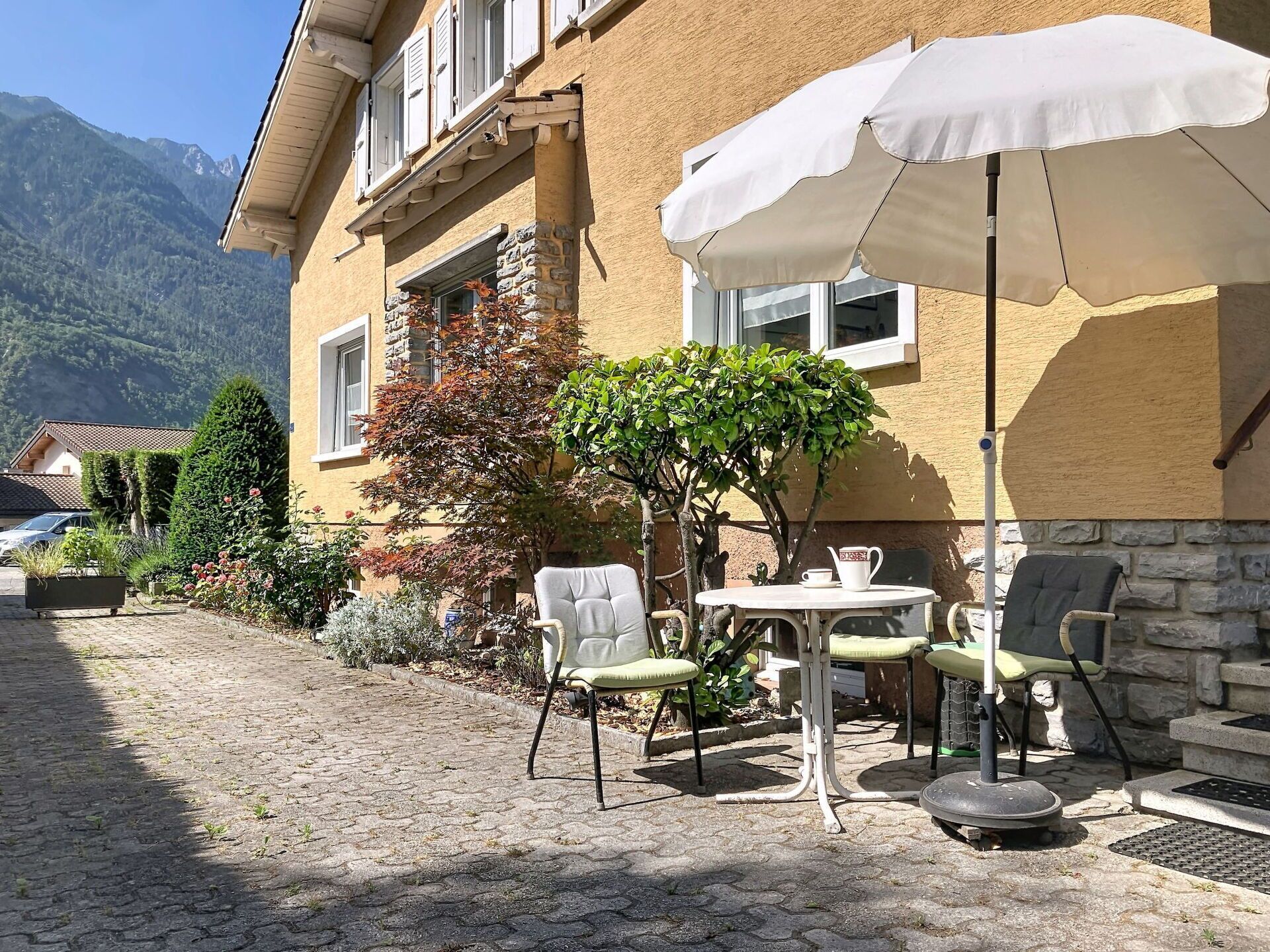 Une terrasse avec des sièges d’extérieur, une table et un parasol blanc.