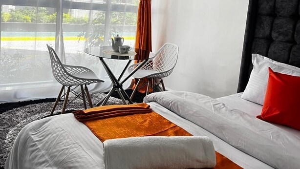 Quarto de hotel com cama, mesa e cadeiras, e vista para o exterior.