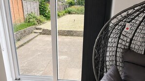 A room with a sliding glass door leading to an outdoor area, a black mesh chair, and a wooden floor.